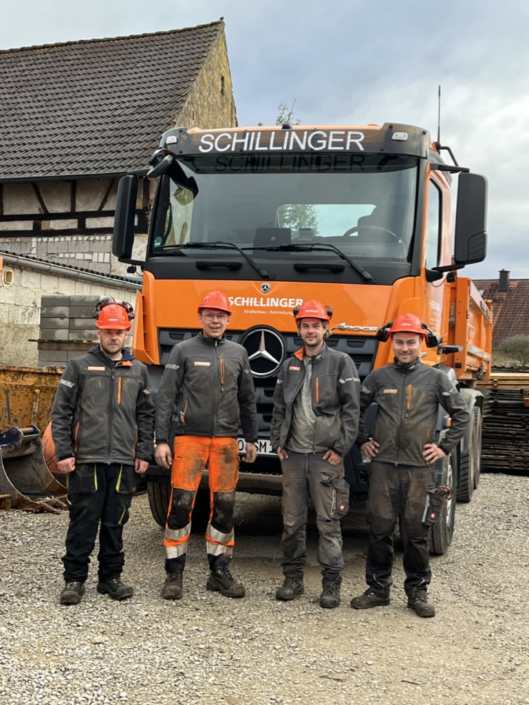 Ein Teil des Teams von Schillinger in Arbeitskleidung vor schwerem Gerät